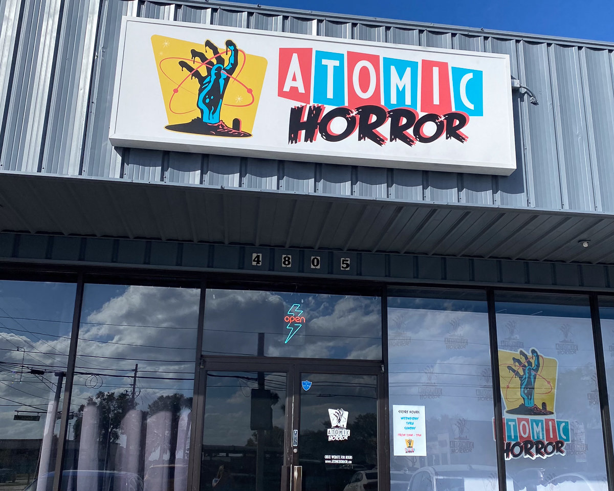 front of atomic horror shop with red and blue sign with logo